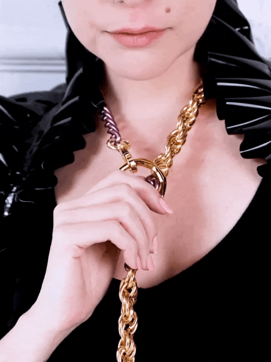 Sexy woman wearing long chain collar with cuffs in purple gold color and black latex accessories