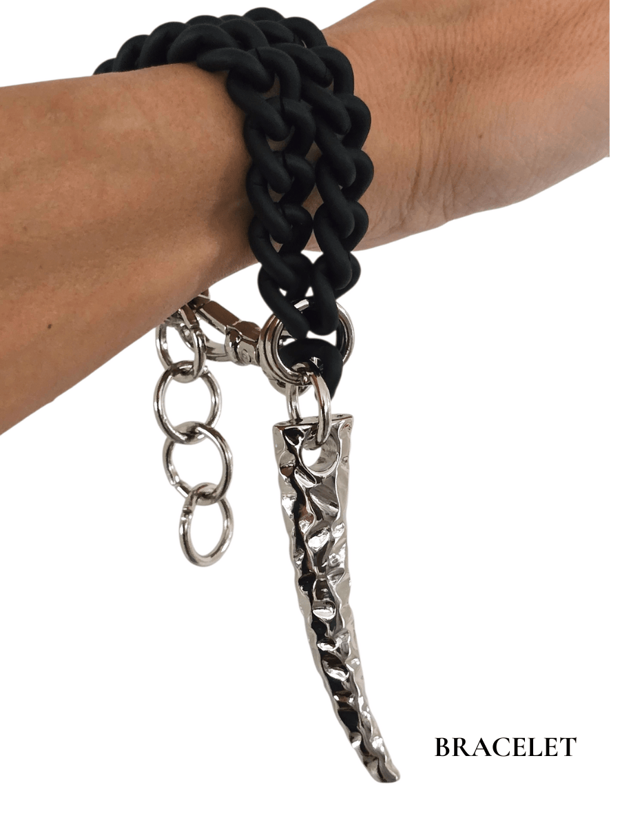 Black chain bracelet with silver charms on a wrist against a white background