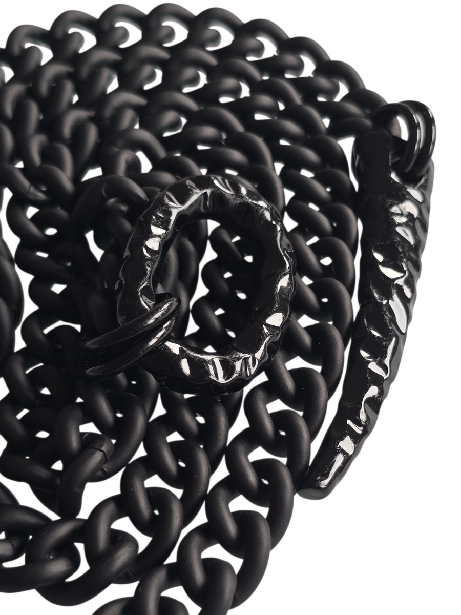 Black chain necklace detail of shiny black oval and claw on white background