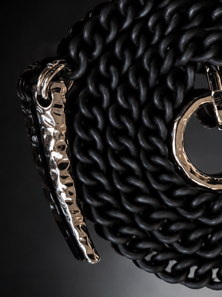 A close-up of a black chain belt with a polished hammered silver horn