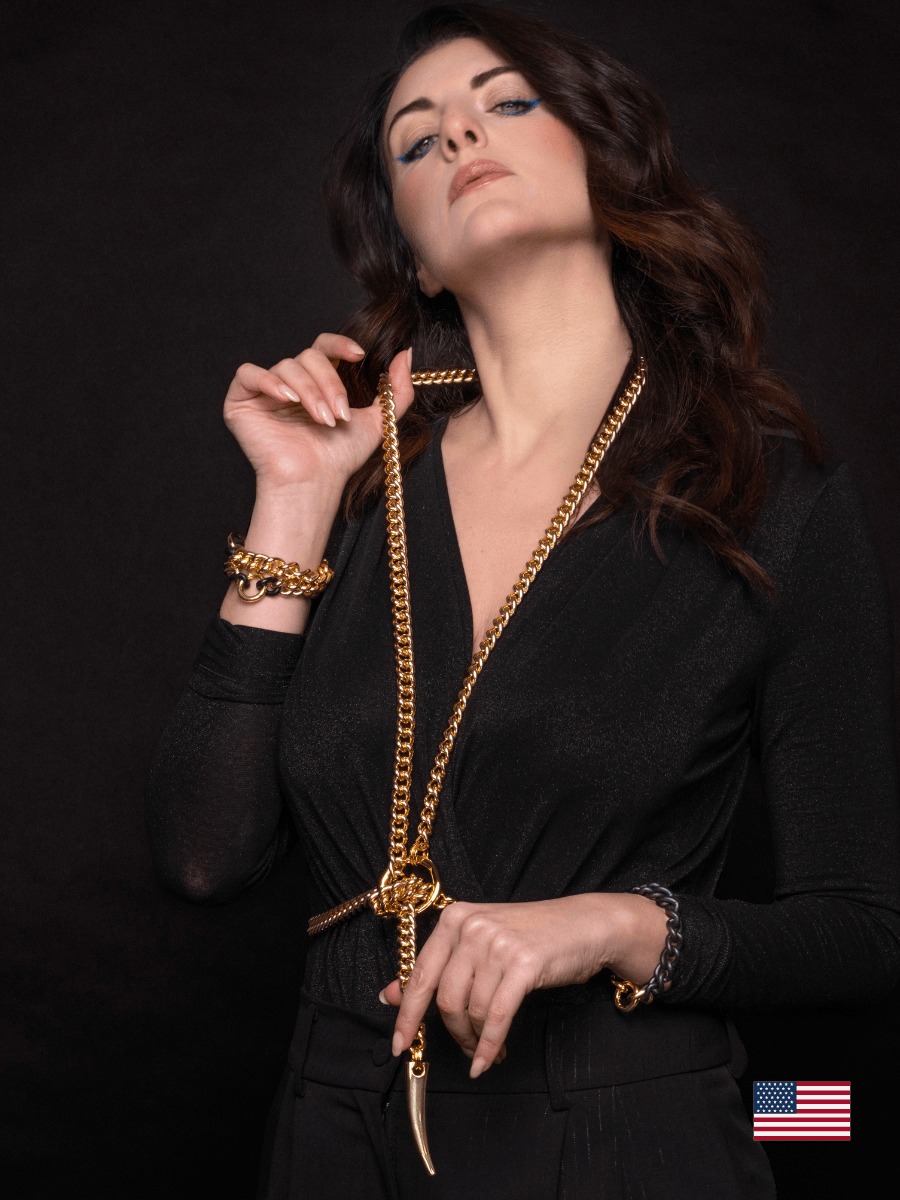 Woman wearing a gold body chain necklace against a black background