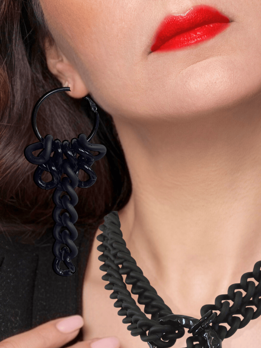 Close-up of a person wearing a black hoop earring and necklace with red lipstick.