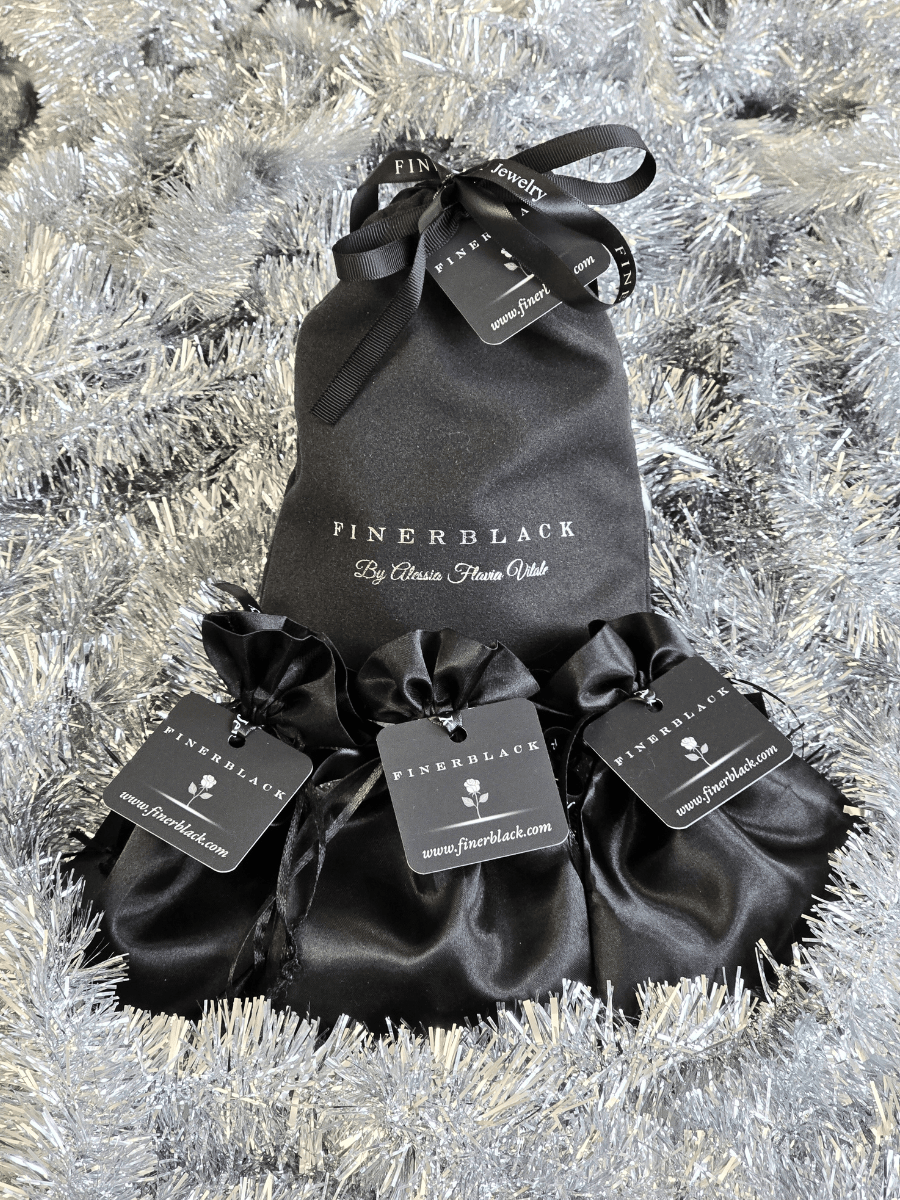 Black satin drawstring bags with 'FINERBLACK' branding on a silver tinsel background.