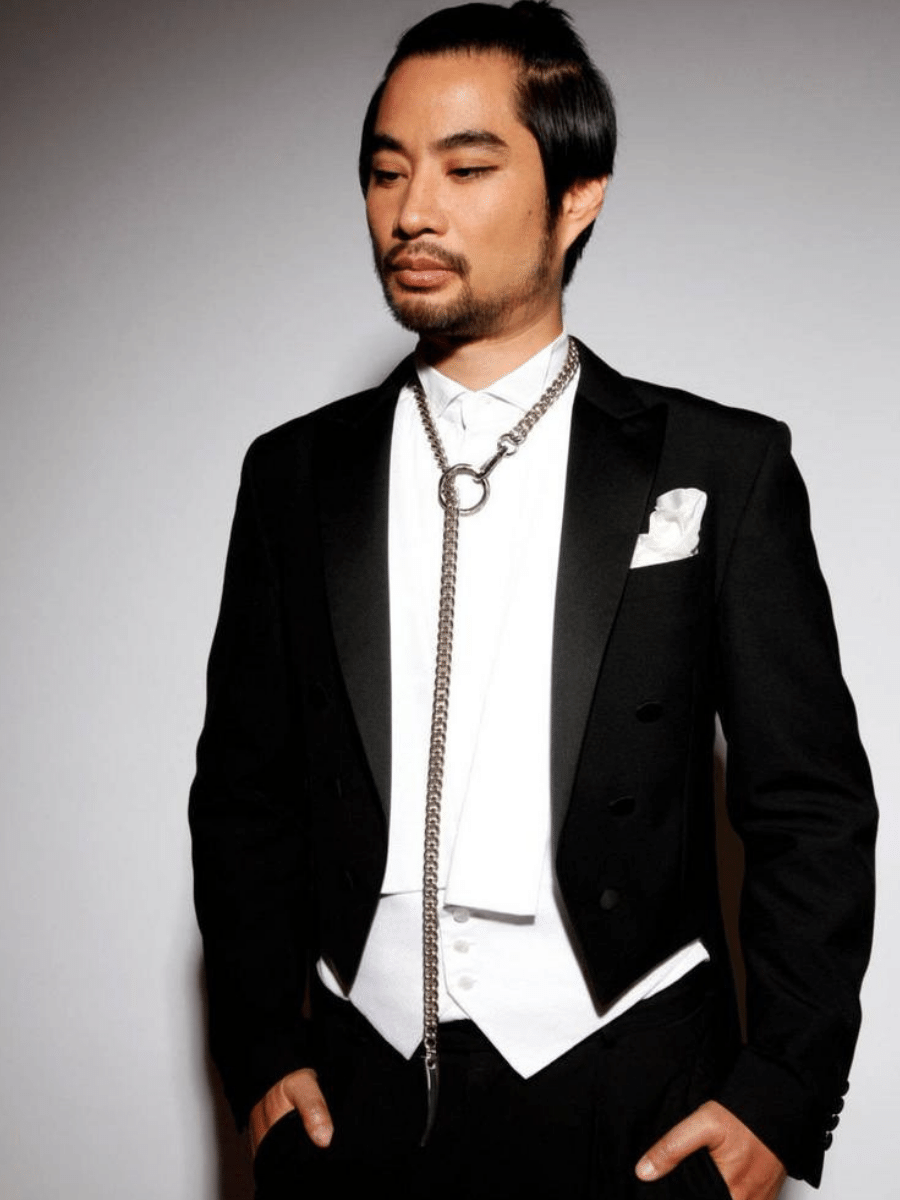 man wearing a tuxedo with long o ring chain necklace