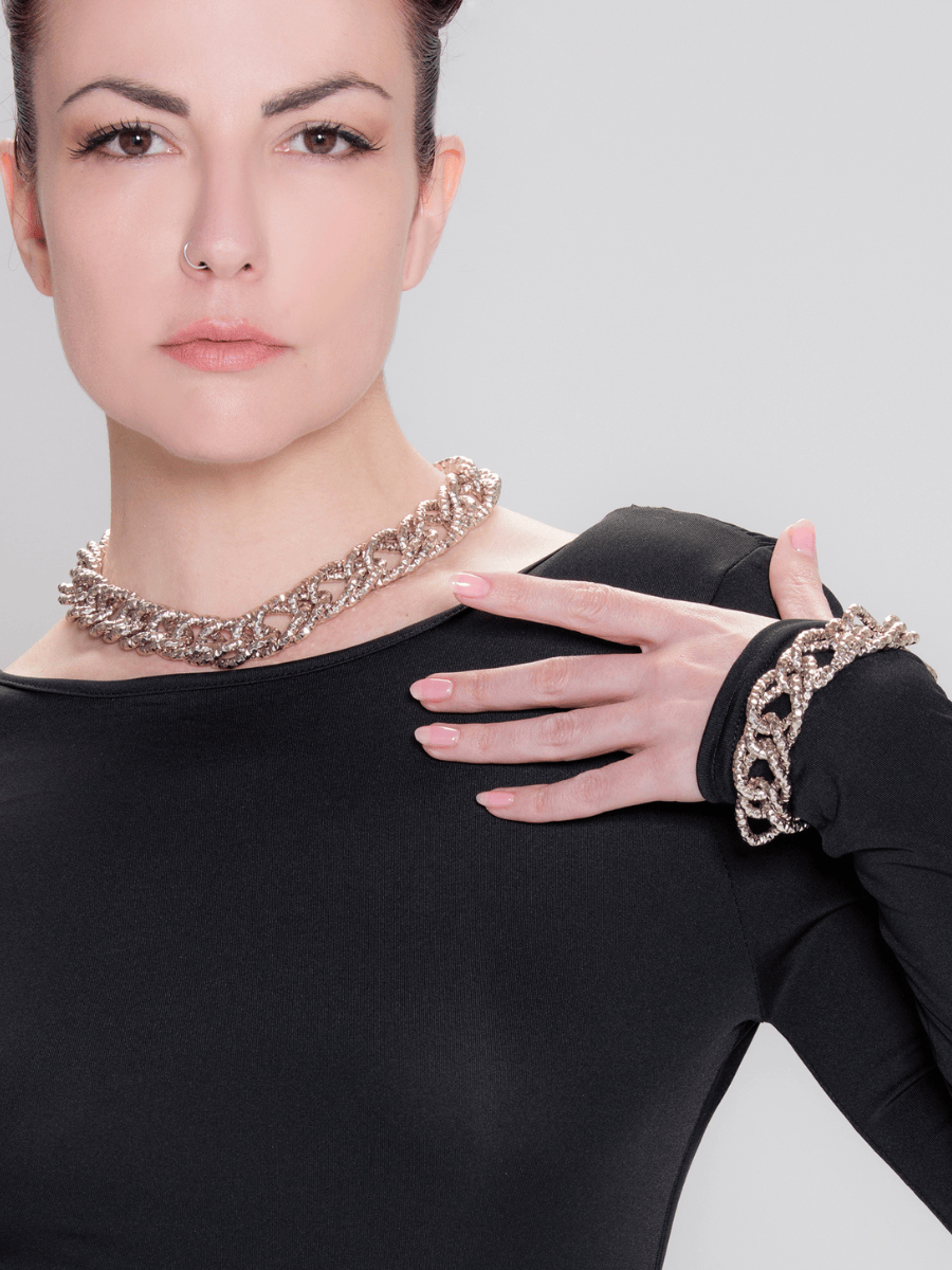 Woman wearing a black outfit with silver jewelry on a gray background